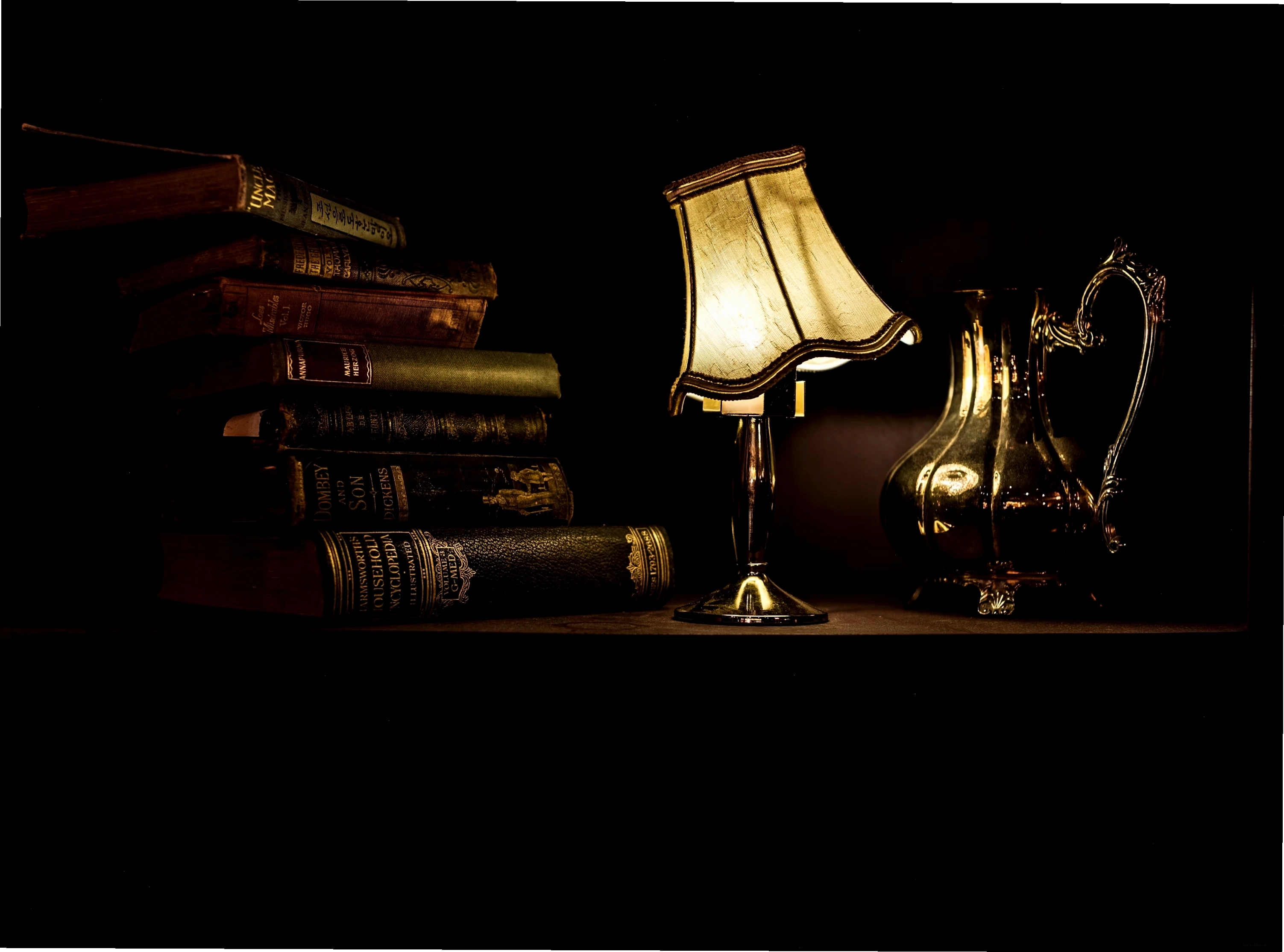 Turned on desk lamp beside a pile of vintage books